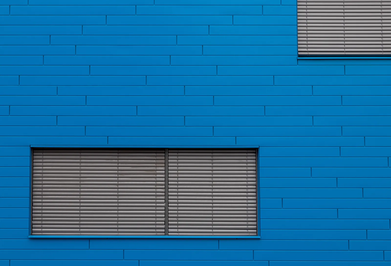 Fachada azul com estores exteriores de lâminas